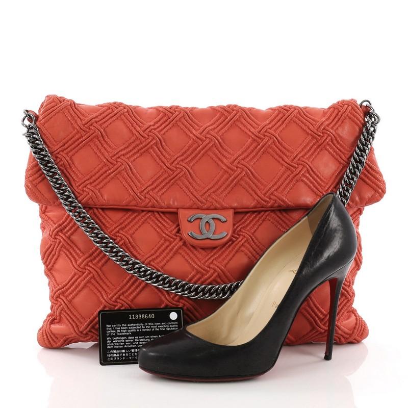 This Chanel Walk of Fame Flap Bag Quilted Lambskin Large, crafted in red orange smocked stitch quilted lambskin leather, features bijoux chain strap, metal CC logo and gunmetal-tone hardware. Its magnetic snap button closure opens to a grey satin