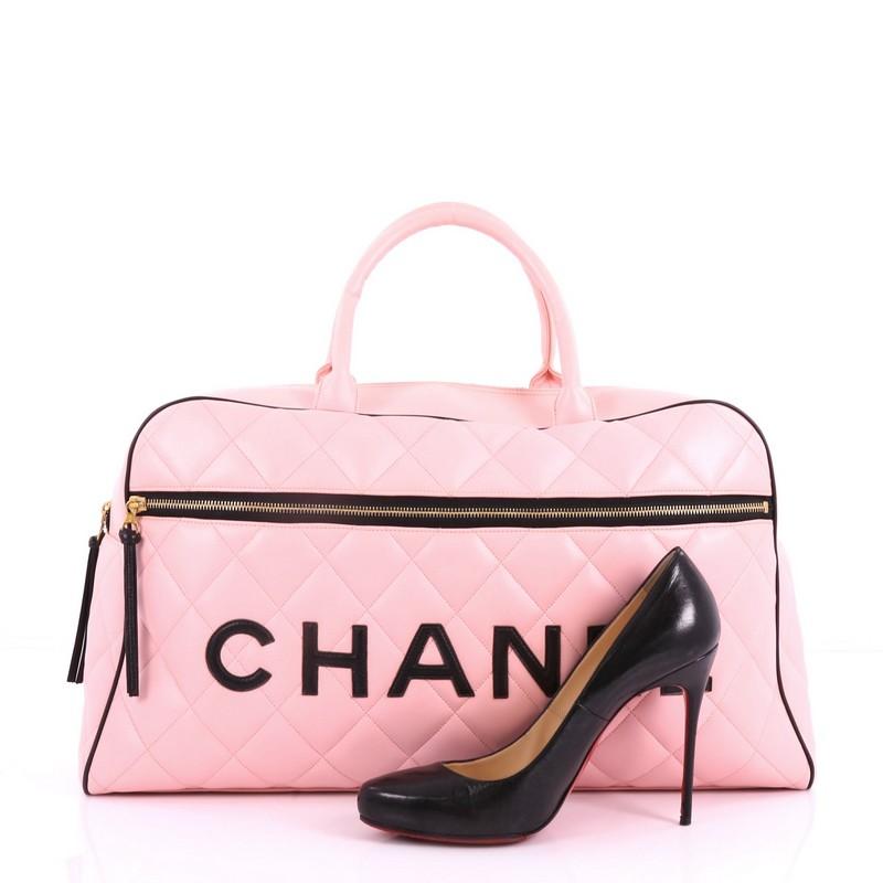This Chanel Vintage Logo Bowler Bag Quilted Lambskin Large, crafted in pink quilted lambskin, features dual rolled leather handles, logo leather lettering stitched across the front, and gold-tone hardware. Its top zip closure opens to a black