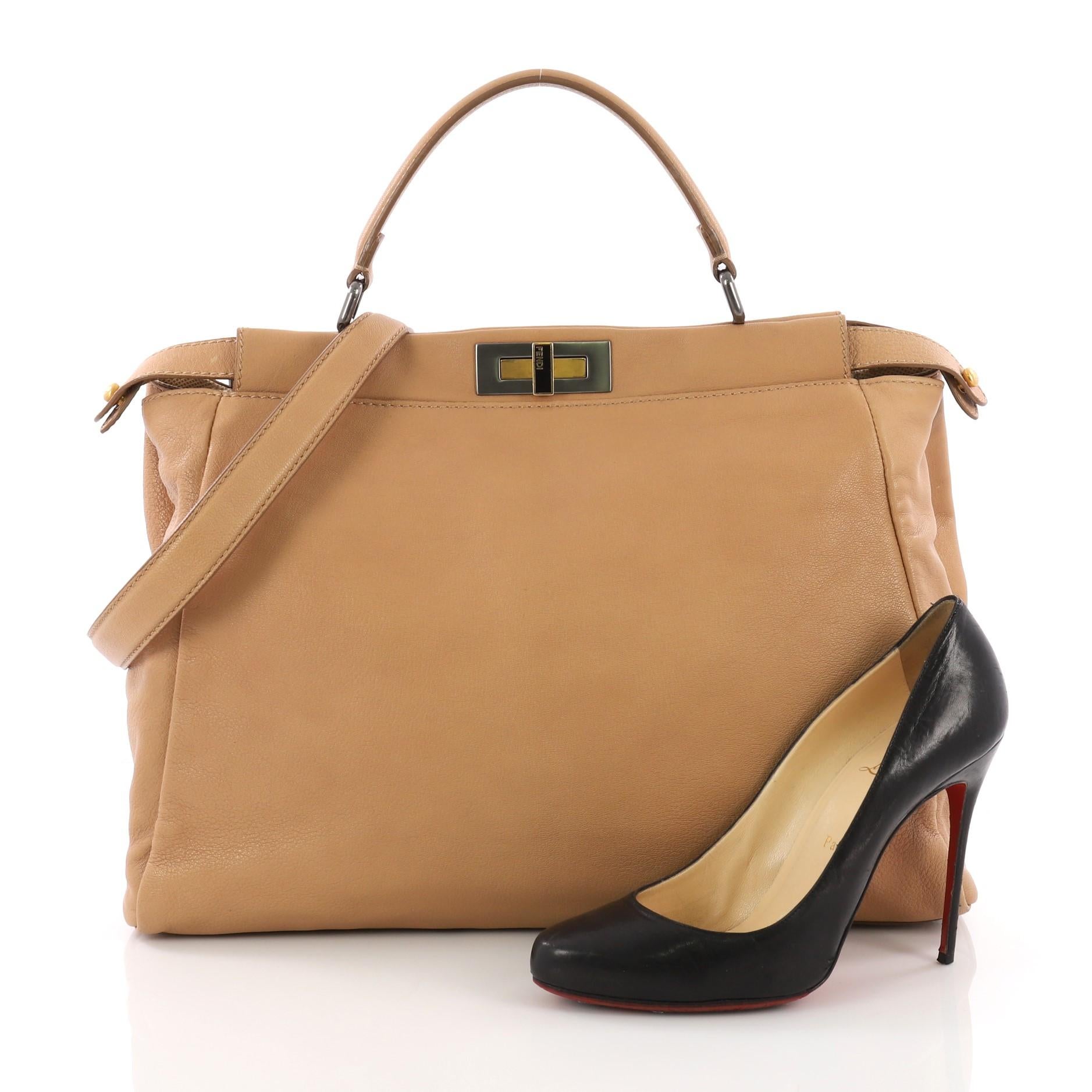 This Fendi Peekaboo Handbag Leather Large, crafted in brown leather, features a flat leather top handle, protective base studs and gunmetal and gold-tone hardware accents. Its turn-lock closures on both sides opens to a beige fabric interior with a