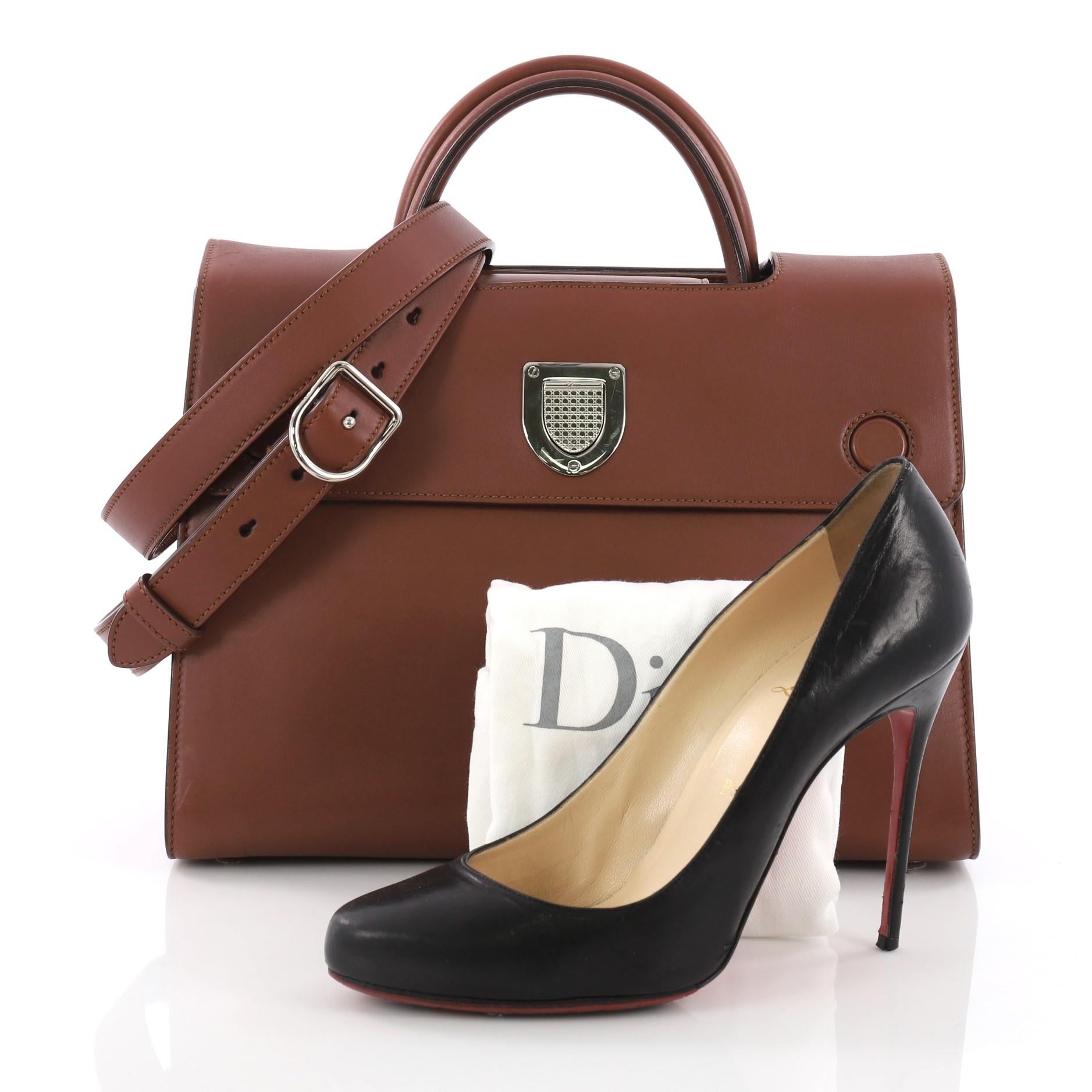 This Christian Dior Diorever Top Handle Bag Leather Medium, crafted in brown leather, features dual rolled leather handles, side snap buttons and silver-tone hardware. Its textured push-lock closure opens to a brown leather interior with slip