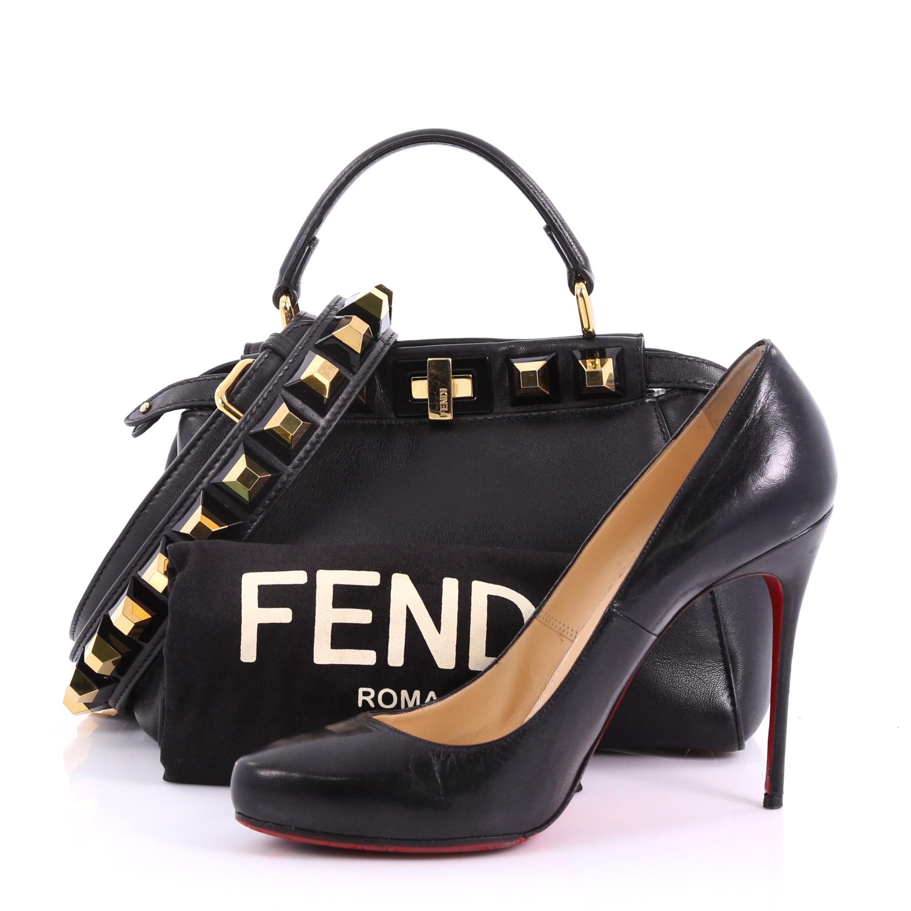This Fendi Peekaboo Handbag Leather with Studded Detail Mini, crafted in black leather with studded detail, features flat leather top handle, stud detailing, and gold-tone hardware. Its turn-lock closures on both sides opens to a black leather