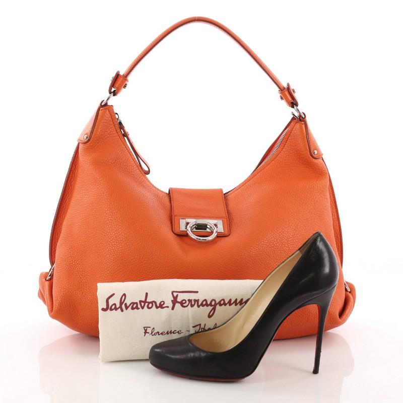 This Salvatore Ferragamo Fanisa Hobo Leather Medium, crafted in orange leather, features a single looped leather strap, Gancini rings on both sides and silver-tone hardware. Its flip-lock Gancini and zip closure opens to a brown fabric interior with
