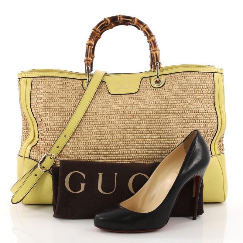 This Gucci Bamboo Shopper Tote Straw Large, crafted from yellow leather and straw, features bamboo handles, protective base studs, and gold-tone hardware. Its magnetic tab closure opens to a multicolor fabric interior divided into two compartments