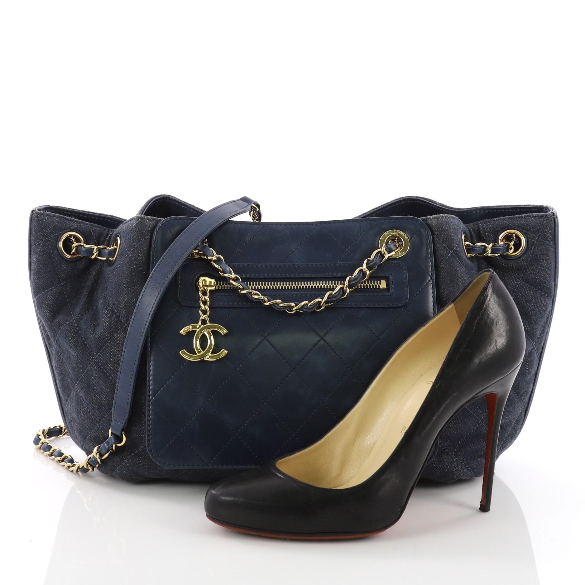 This Chanel Drawstring Shoulder Bag Quilted Denim and Aged Calfskin Medium, crafted from blue quilted denim and aged calfskin, features woven-in leather chain straps with leather shoulder pad, exterior front zip pocket, and gold-tone hardware. Its
