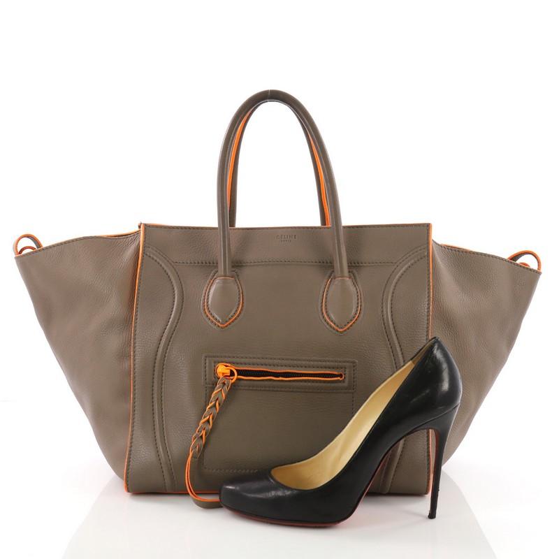 This Celine Phantom Handbag Grainy Leather Medium, crafted in dark taupe grainy leather, features dual rolled leather handles, front zip pocket, and black and orange-tone hardware. It opens to a gray suede interior with zip pocket. **Note: Shoe