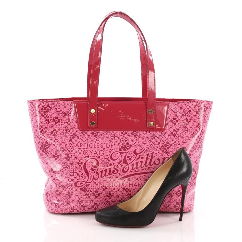 This Louis Vuitton Voyage Tote Cosmic Blossom PM, crafted from pink patent leather with cosmic monogram flower prints, features dual-flat patent leather handles, protective base studs and gold-tone hardware. Its hook clasp closure opens to a pink