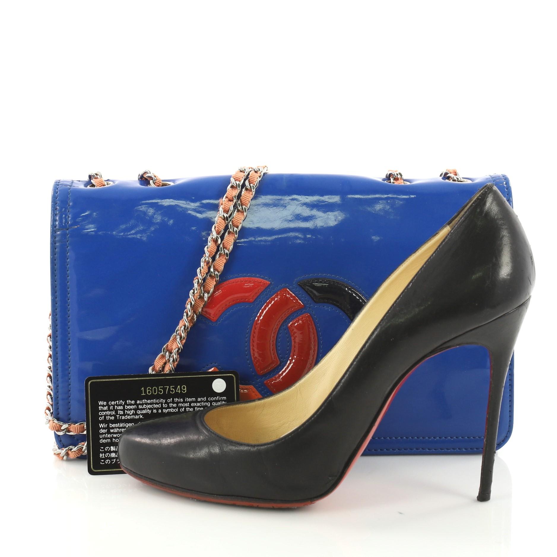 This Chanel Lipstick Flap Bag Patent Vinyl Small, crafted from blue patent vinyl, features woven-in leather silver chain straps and silver-tone hardware. Its hidden magnetic snap closure opens to a red fabric interior with side zipped pocket.