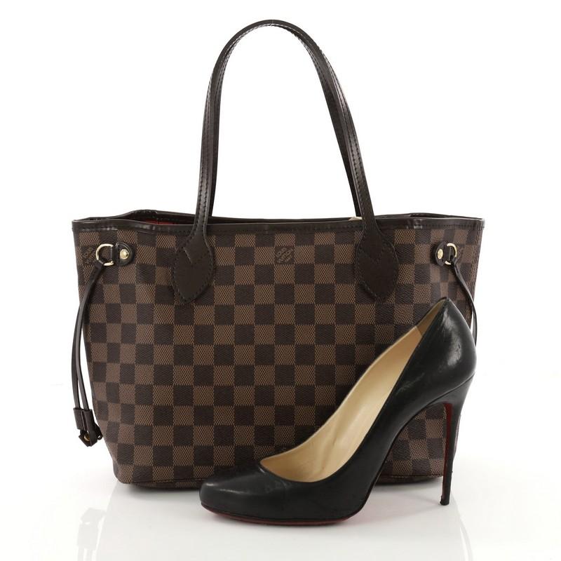 This Louis Vuitton Neverfull Tote Damier PM, crafted in damier ebene coated canvas, features dual slim handles, side laces and gold-tone hardware. Its wide open top showcases a red striped fabric interior with side zip pocket. Authenticity code