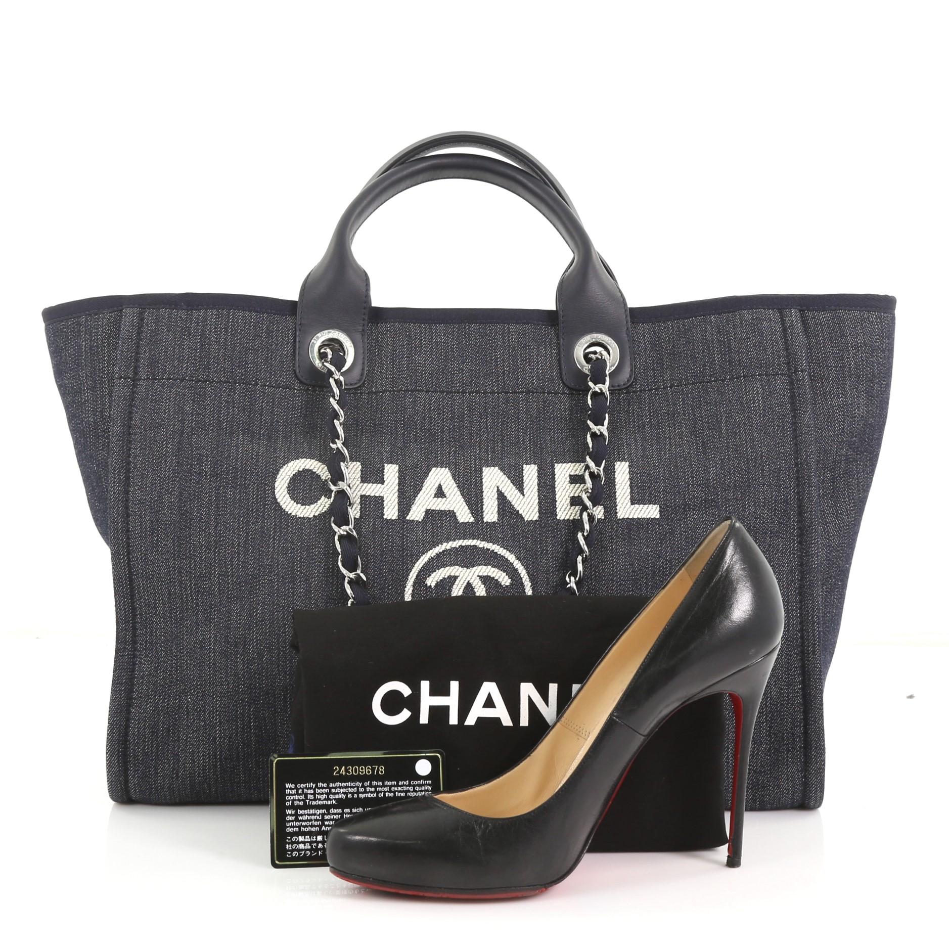 This Chanel Deauville Chain Tote Denim Medium, crafted in blue denim, features dual rolled leather handles, woven-in chain link straps, printed CC logo with Chanel's famous Parisian store address and silver-tone hardware. Its magnetic snap closure
