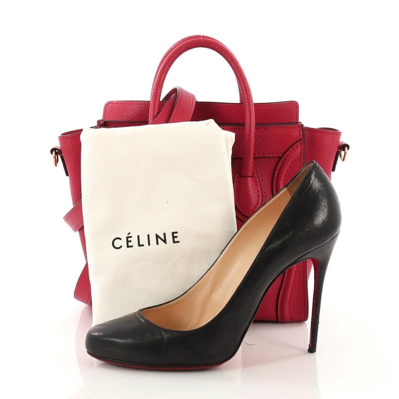 This Celine Luggage Handbag Grainy Leather Nano, crafted in red grainy leather, features dual-rolled leather handles, exterior front zip pocket, and gold-tone hardware accents. Its zip closure opens to a red microfiber interior with slip pocket.