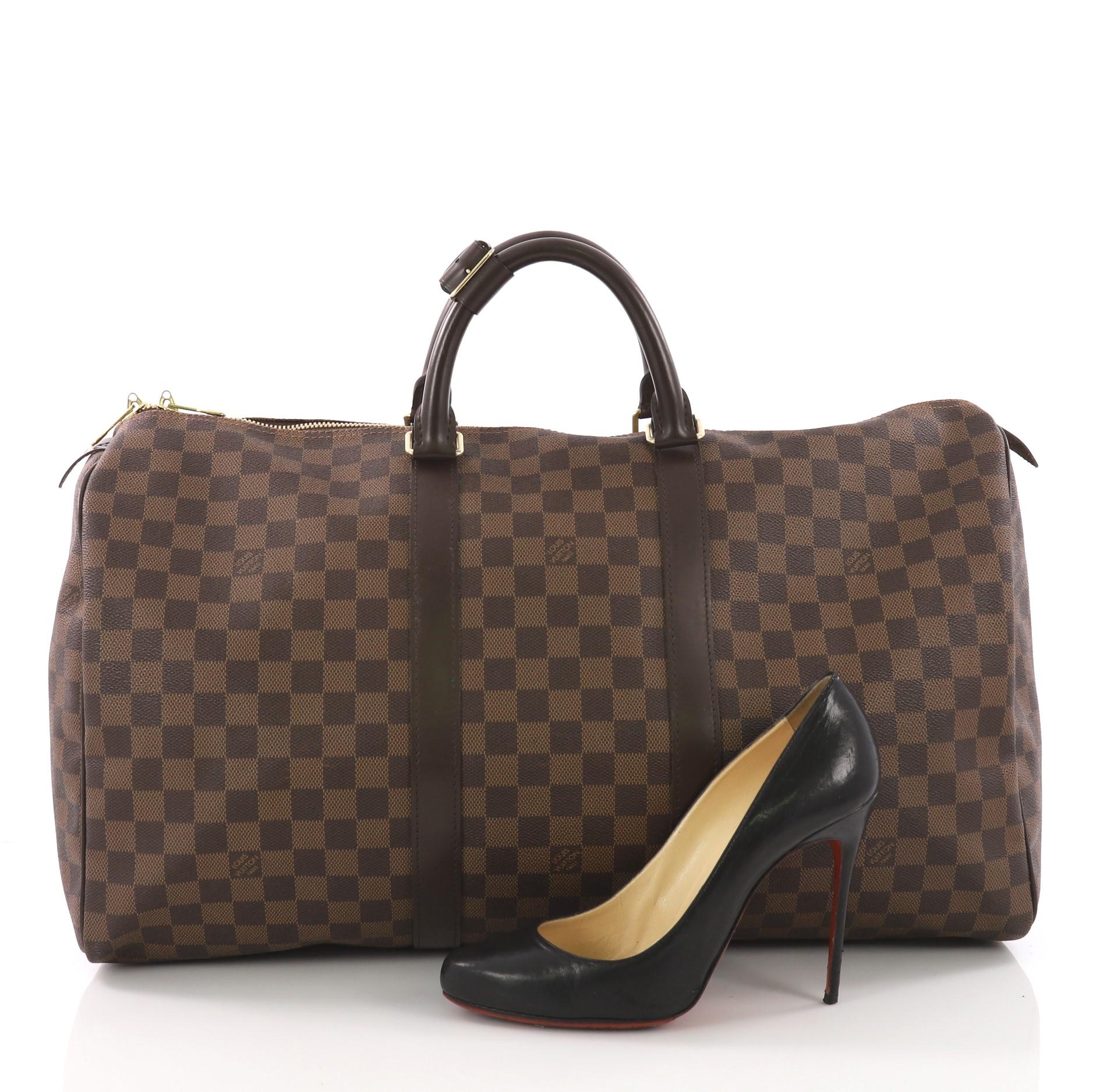 This Louis Vuitton Keepall Bag Damier 50, crafted in damier ebene coated canvas, features dual rolled handles and gold-tone hardware. Its dual-zip closure opens to a brown fabric interior. Authenticity code reads: MB2160. **Note: Shoe photographed