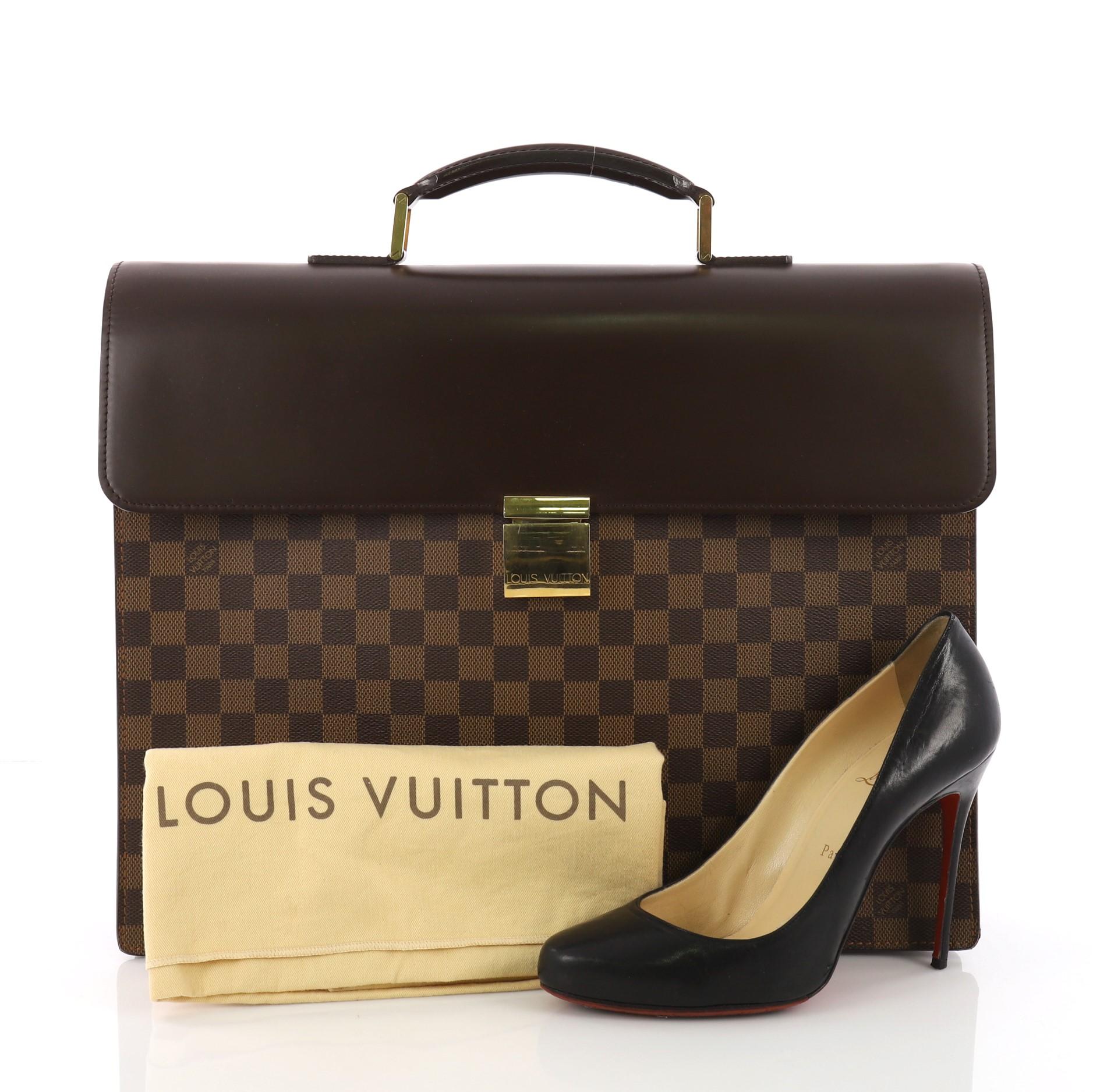 This Louis Vuitton Altona Bag Damier PM, crafted from damier ebene coated canvas, features leather top handle, exterior back slip pocket and gold-tone hardware. Its latch closure opens to a brown microfiber interior with slip pockets. Authenticity