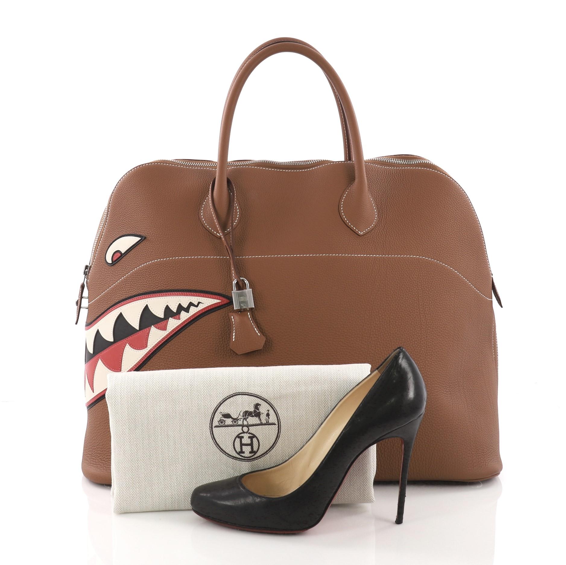 This Hermes Limited Edition Shark Bolide Togo 45, crafted from brown togo leather, features a shark leather applique on the corner of the bag, dual rolled leather handles, and silver-tone hardware. Its zip closure opens to a beige fabric interior.