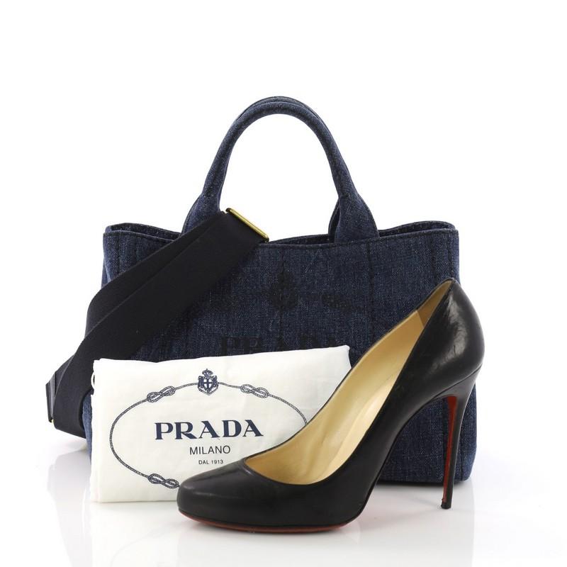 This Prada Canapa Convertible Tote Denim Mini, crafted from blue denim, features dual handles, side snap buttons, protective base studs, and gold-tone hardware. Its wide top opening showcases a blue denim interior with zip and slip pockets **Note: