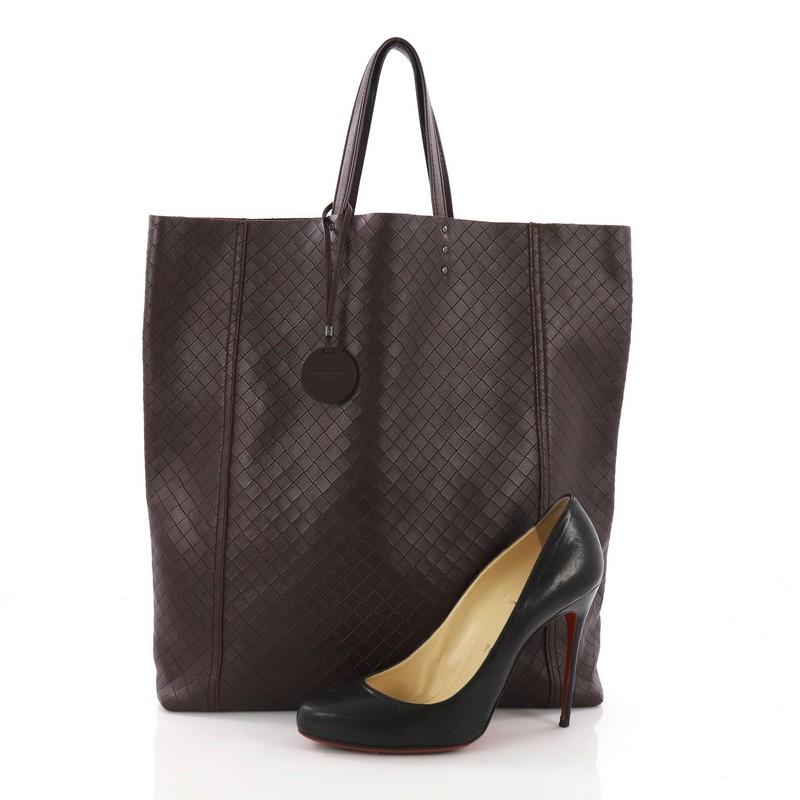 This Bottega Veneta Vertical Tote Intrecciomirage Leather Small, crafted in purple Intrecciomirage leather, features dual flat handles, pendant with butterfly insignia, and gunmetal and silver-tone hardware. Its wide open top showcases a matching
