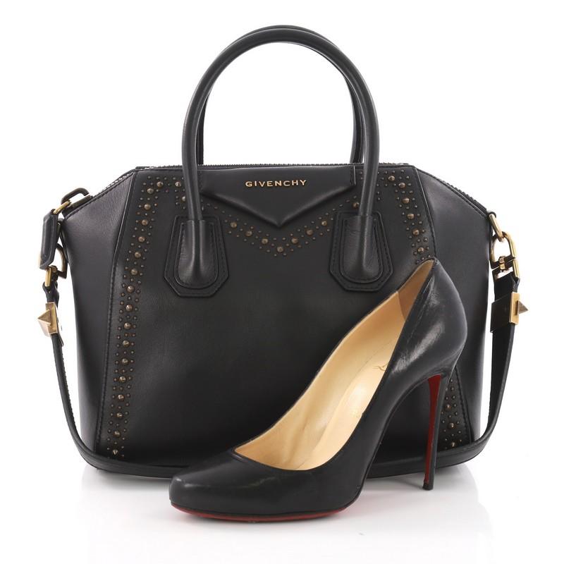 This Givenchy Antigona Bag Studded Leather Small, crafted from studded black leather, features Givenchy's signature envelope fold logo in front, dual top handles, and brass-tone hardware. Its top zipper closure opens to a black fabric interior with