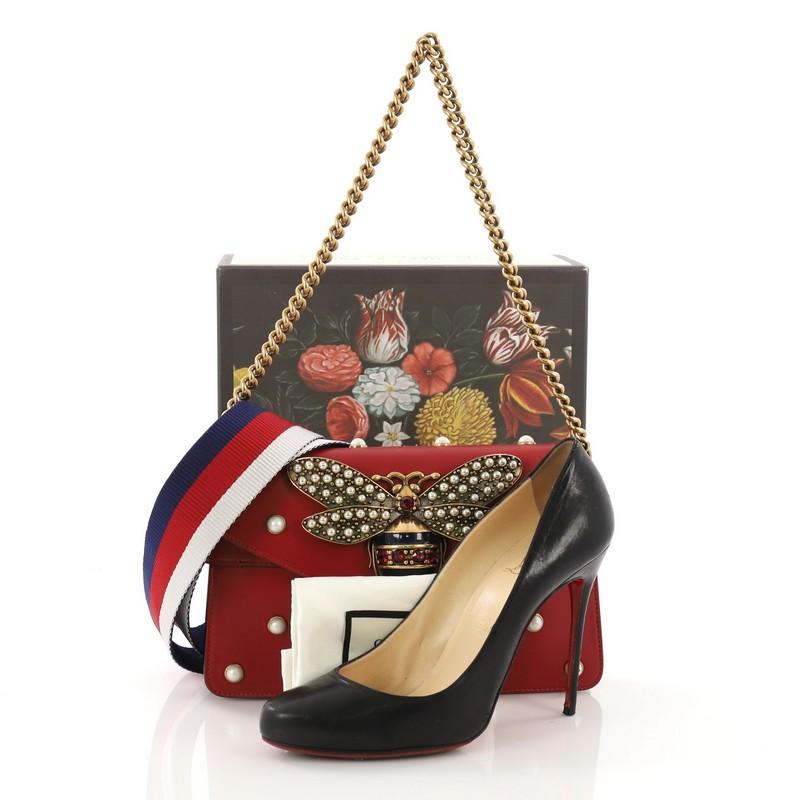 This Gucci Broadway Pearly Bee Shoulder Bag Embellished Leather Mini, crafted from red leather, features chain link strap, multiple pearl studs, metal bee design and aged-gold tone hardware. Its flap closure opens to a nude leather interior with