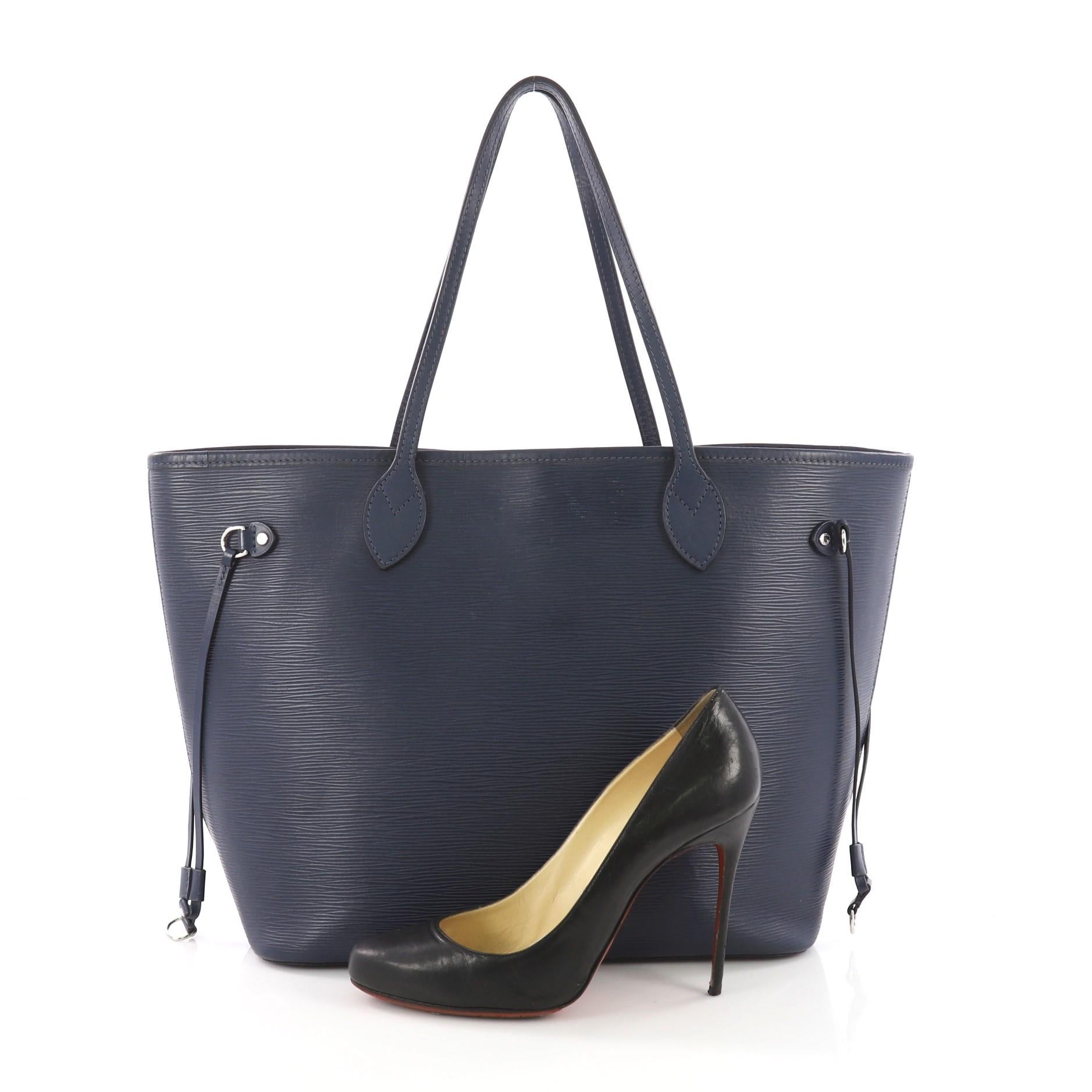 This Louis Vuitton Neverfull Tote Epi Leather MM, crafted in navy blue epi leather, features dual flat leather handles, side tassels, and silver-tone hardware. Its wide open top opens to a blue microfiber interior. **Note: Shoe photographed is used