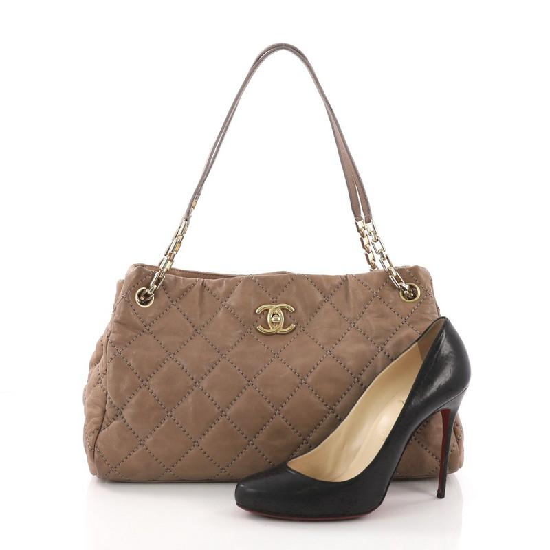 This Chanel Retro Chain Tote Quilted Calfskin Medium, crafted in brown quilted calfskin leather, features dual leather handles with chain links, protective base studs, and gold-tone hardware. Its CC turn-lock and zip closure opens to a beige fabric