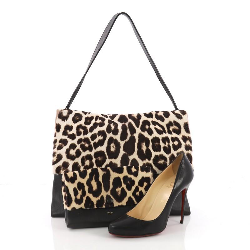 This Celine All Soft Tote Printed Pony Hair with Leather, crafted in brown and black printed pony hair with leather, features a flat leather shoulder strap and gold-tone hardware. Its flap opens to a black leather interior. **Note: Shoe photographed