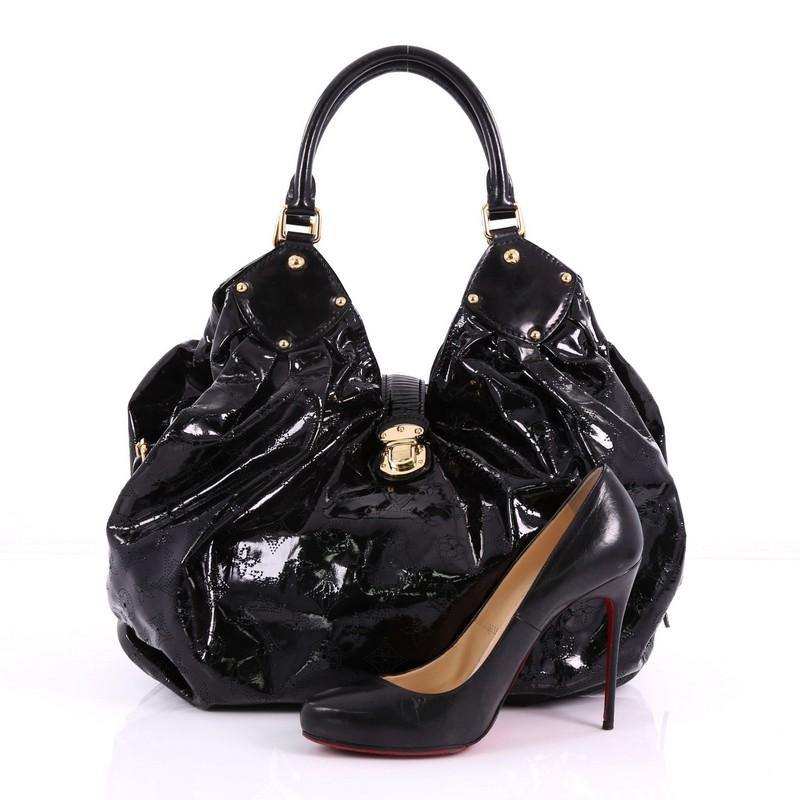 This Louis Vuitton XL Hobo Surya Leather, crafted from LV’s black Surya leather, features dual rolled handles, buckle and stud details, gold-tone hardware. Its engraved top flap push-lock closure opens to a black microfiber interior with side zip