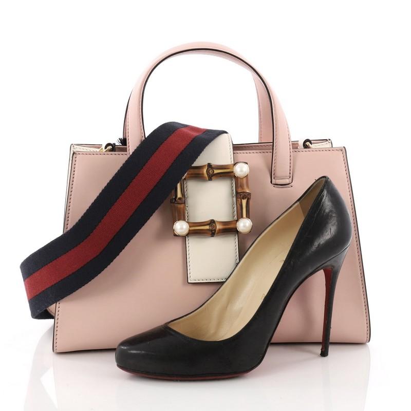 This Gucci Convertible Bamboo Buckle Tote Leather Medium, crafted in pink leather, features dual flat leather handles and gold-tone hardware. Its leather tab with bamboo closure opens to a gray microfiber interior with side zip and slip pockets.