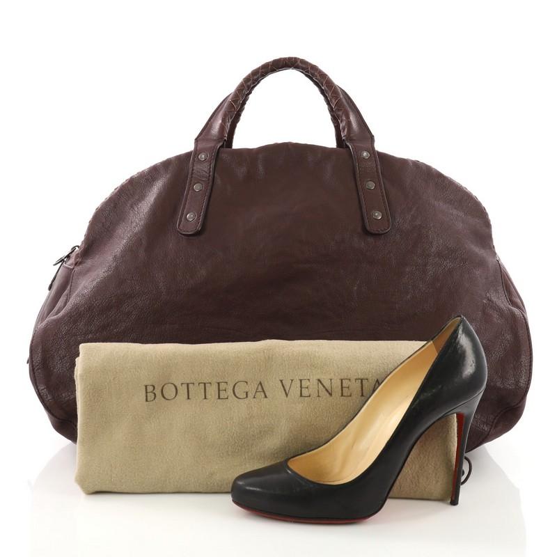This Bottega Veneta Weekender Bag Leather with Intrecciato Detail Large, crafted in dark brown leather, features dual woven top handles and gunmetal-tone hardware. Its zip closure opens to a taupe fabric interior. **Note: Shoe photographed is used