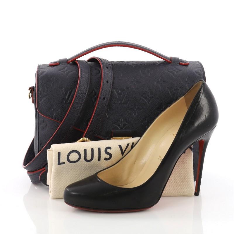 This Louis Vuitton Pochette Metis Monogram Empreinte Leather, crafted in navy blue monogram empreinte leather, features leather top handle, exterior back zip pocket, and gold-tone hardware. Its S-lock closure opens to a red fabric interior with two