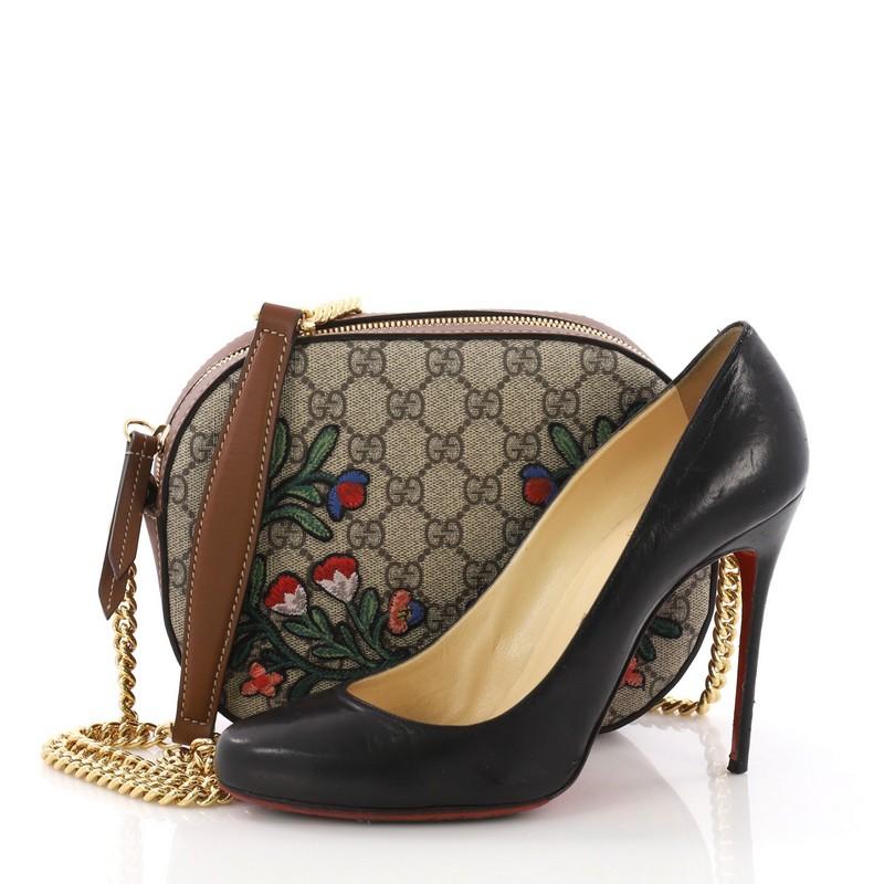 This Gucci Chain Crossbody Bag Embroidered GG Coated Canvas Mini, crafted in brown embroidered GG coated canvas, features chain link strap with leather pad and gold-tone hardware. Its zip closure opens to a blush microfiber interior with slip