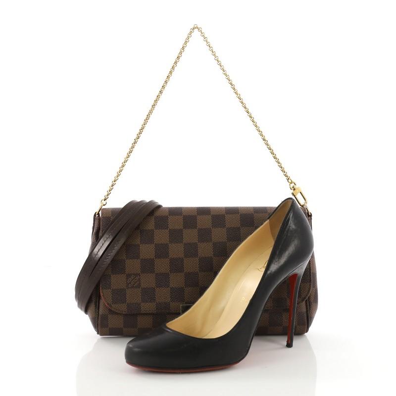 This Louis Vuitton Favorite Handbag Damier MM, crafted from damier ebene coated canvas, features a wristlet chain, dark brown leather trims on the side, and gold-tone hardware. Its flap opens to a red fabric interior with slip pocket. Authenticity