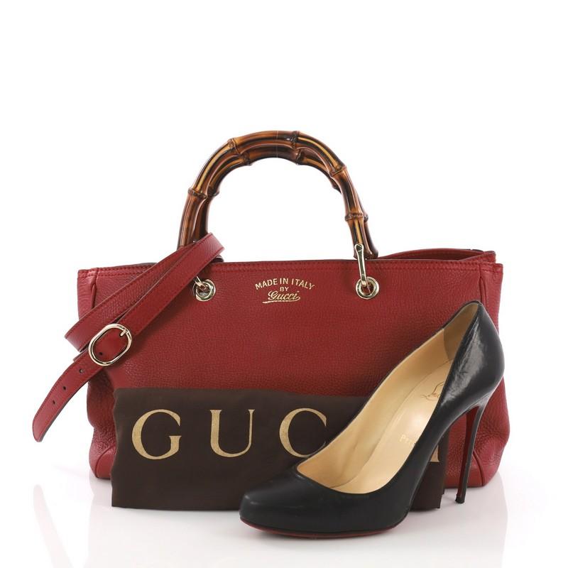 This Gucci Bamboo Shopper Boston Bag Leather Medium, crafted from red leather, features bamboo handles, protective base studs, and gold-tone hardware. It opens to a beige fabric interior with zip and slip pockets. **Note: Shoe photographed is used