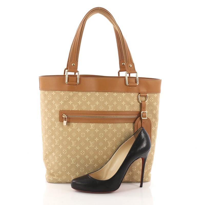This Louis Vuitton Lucille Handbag Mini Lin GM, crafted in beige monogram mini lin canvas, features camel leather trims and handles, front zip pocket, and gold-tone hardware. Its top zip closure opens to a beige fabric interior with side zip and
