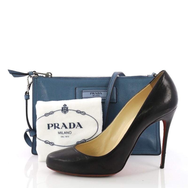 This Prada Etiquette Crossbody Bag Glace Calf Small, crafted in blue glace calf leather, features a detachable shoulder strap, and silver-tone hardware. Its zip closure opens to a blue fabric interior with zip pocket. **Note: Shoe photographed is