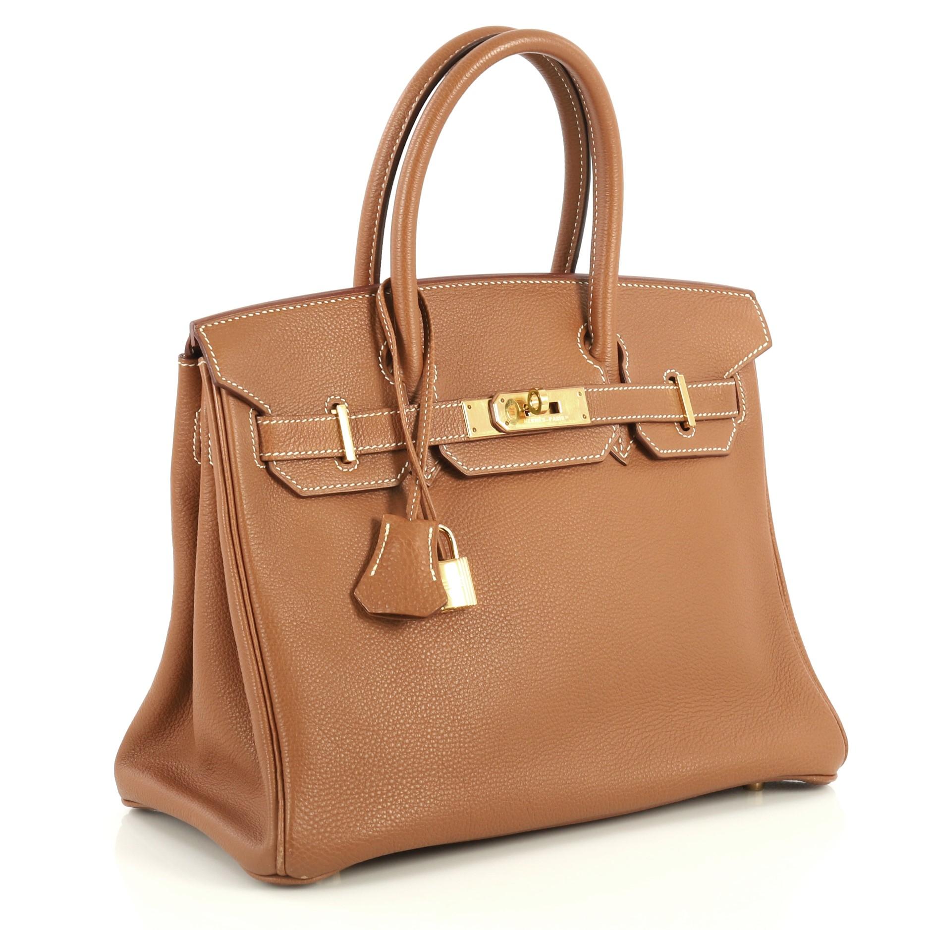 This Hermes Birkin Handbag Gold Togo with Gold Hardware 30, crafted in Gold brown Togo leather, features dual rolled handles, frontal flap, and gold hardware. Its turn-lock closure opens to a Gold brown Chevre leather interior with zip and slip