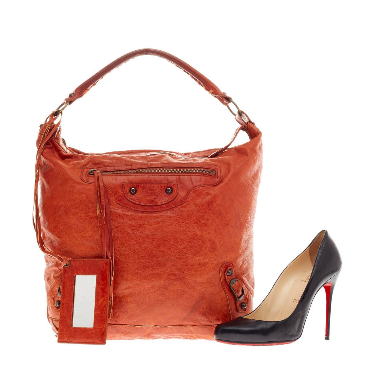 This authentic Balenciaga Day Classic Studs in soft supple red-orange distressed leather is a go-to essential that fits everyday essentials. This spacious hobo is accented with an intertwined braided leather top handle, long fringes on front pocket