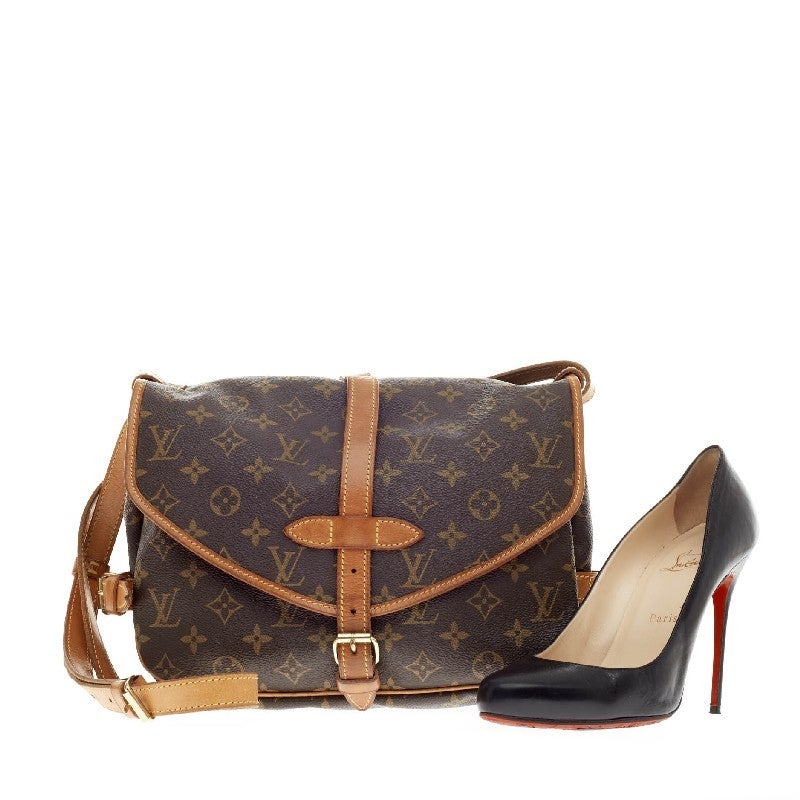 This authentic functional Louis Vuitton Saumur Monogram Canvas in size MM features double saddle compartments with side buckle leather closures and brass closures on the frontal flaps. Its long adjustable straps convert this into a care-free