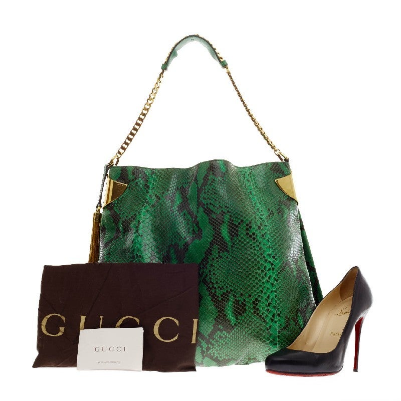 This authentic Gucci 1970 Python Hobo showcases a luxurious and alluring design only from Gucci. Crafted from genuine eye-catching green natural python skin, this exotic hobo features gold side cuff and tassel accents, and gold chain strap with