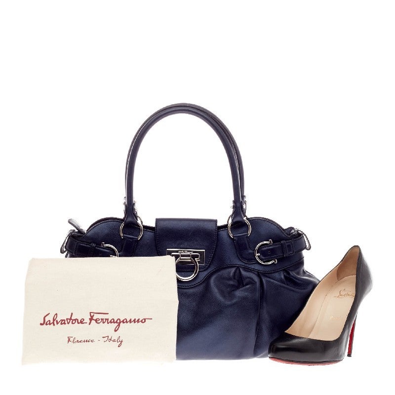 This authentic Salvatore Ferragamo Marisa Satchel Leather is beautifully crafted in metallic blue leather. This bag features a signature top flap silver-tone Ferragamo Gancini lock closure. The interior opens to a designer-lined fabric in gray and