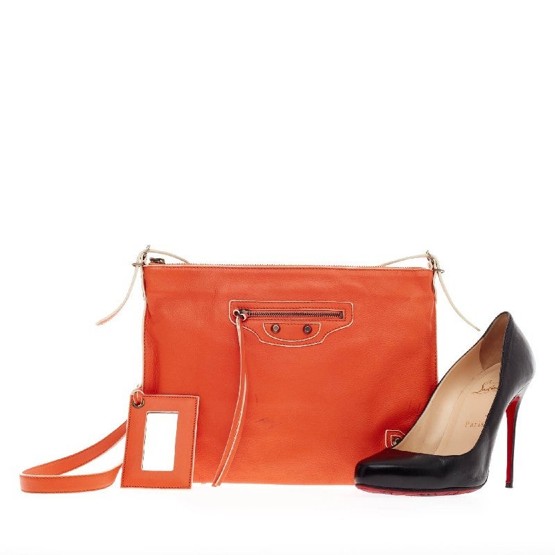 This authentic Balenciaga Papier Neo Crossbody Leather bag is a sleek and versatile staple piece for any day. Constructed from bright orange supple leather, this versatile flat messenger features detachable cross-body straps that allows it to