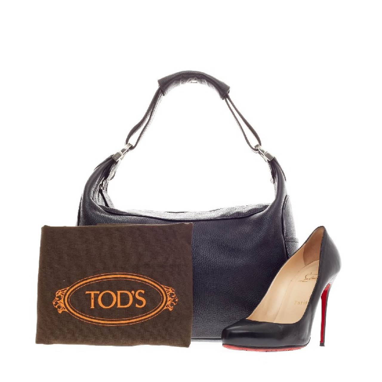 This authentic Tod's Zip Shoulder Bag Leather is perfect for everyday use. Constructed from black leather, this bag features single shoulder strap with pad, exterior side pockets with embossed Tod's logo and silver hardware accents. Its top zipped