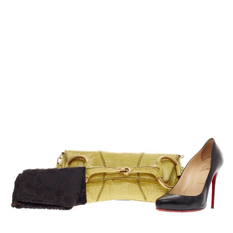 This authentic Gucci Horsebit Chain Strap Clutch Crocodile is luxuriously elegant and perfect for a day or a night out. Crafted from genuine yellow crocodile, this chic clutch features a large horsebit design at its front and gold-tone hardware