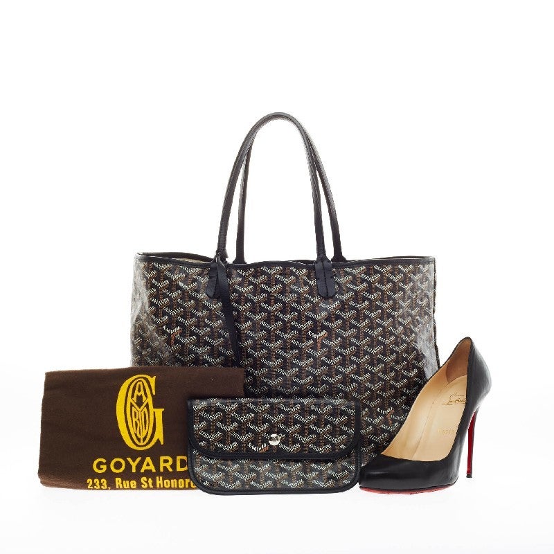 This authentic Goyard St. Louis Canvas PM is crafted from the popular and traditional black, cognac and creme Goyard chevron canvas. This spacious tote features long, thin rolled leather top handles and black trim details. Its open top showcase a