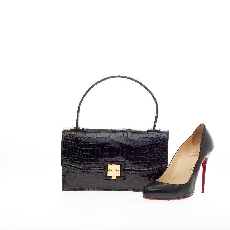 This authentic rare Hermes St. Honore Crocodile Porosus inspired by their historic location is a coveted luxurious piece that stands the test of time. Crafted from genuine sleek black shiny crocodile skin, this structured petite vintage top handle