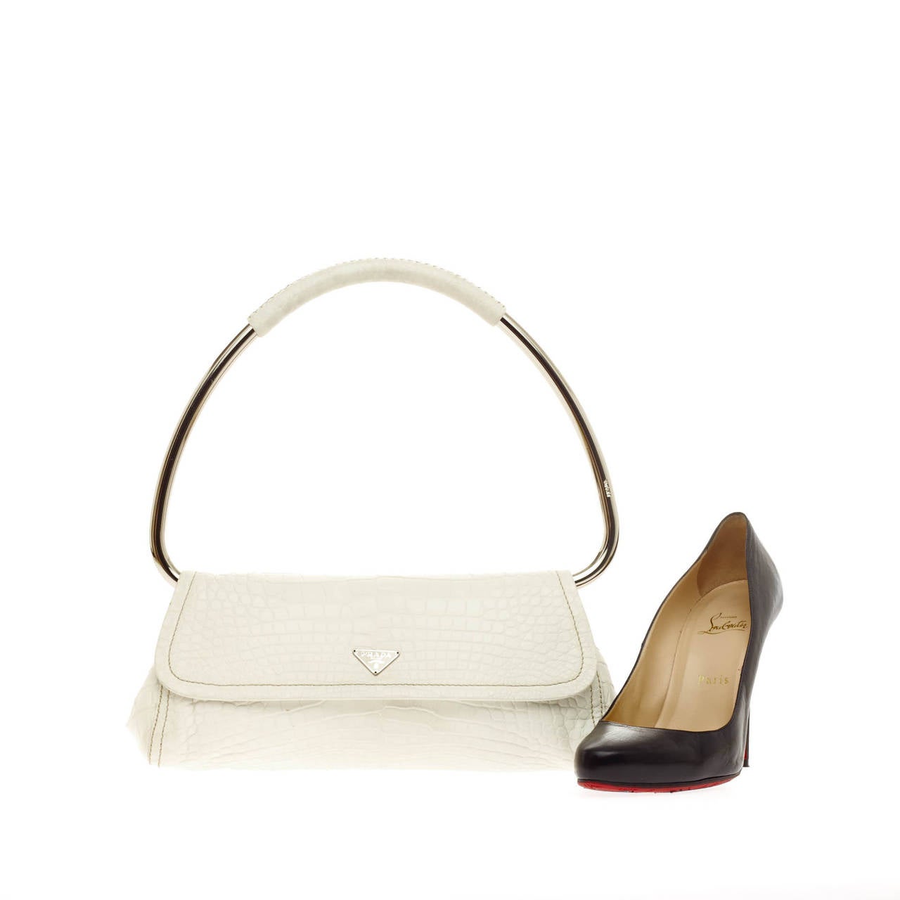 This authentic Prada Ring Handle Bag Crocodile is simple yet stylish for everyday use. Created from genuine white crocodile skin, this luxuriously minimalist handle bag features a unique silver looped ring handle, side silver snaps and iconic Prada