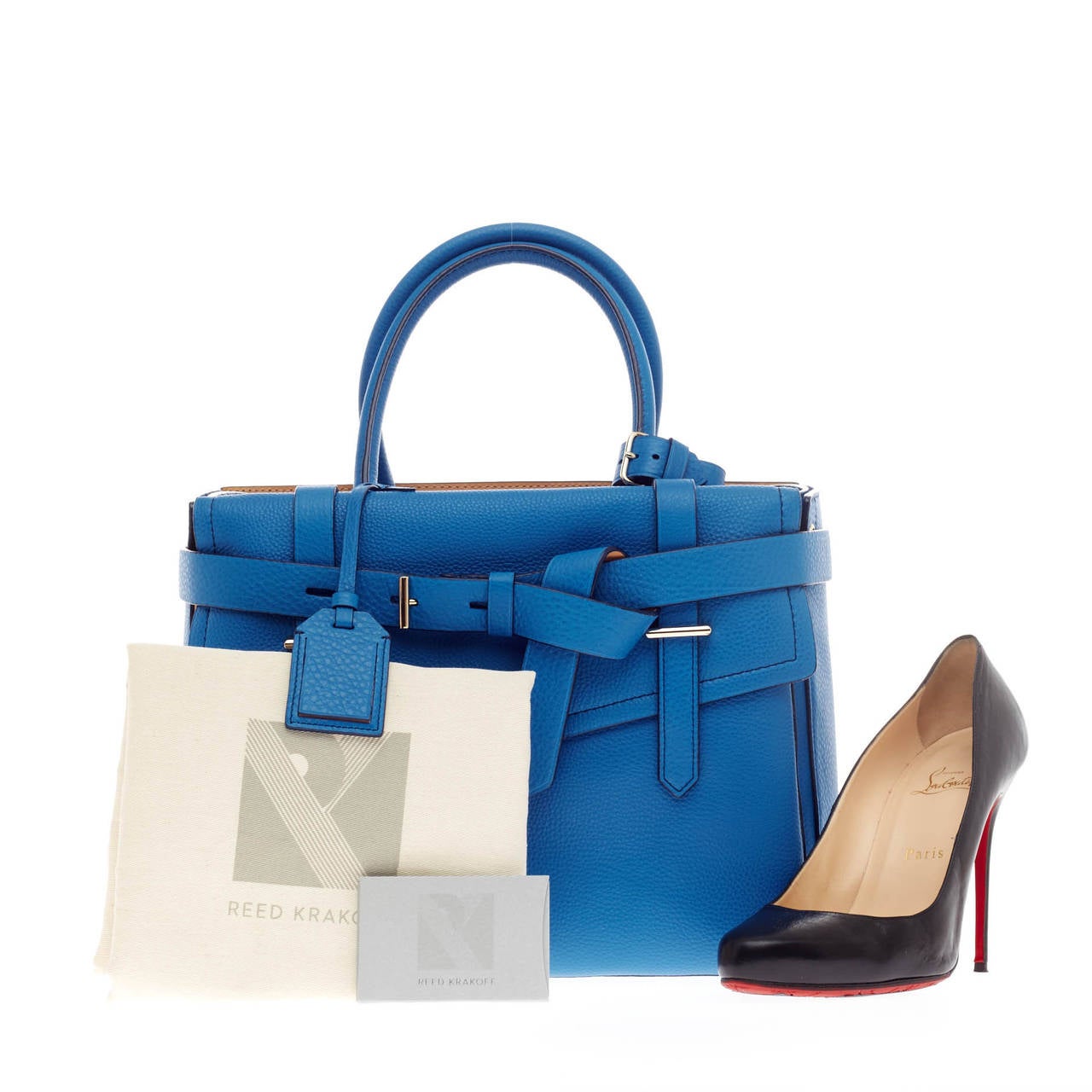 This authentic Reed Krakoff Boxer Tote Leather Medium is a versatile structured bag with an added pop of color for a playful twist. Constructed in striking caribbean blue leather, this functional tote features wrap-around leather buckle strap