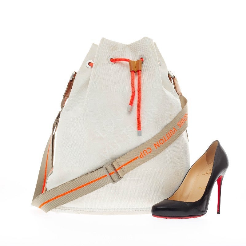 This authentic limited edition Louis Vuitton Geant Drawstring Shoulder Bag Canvas created for the LV Cup is your perfect companion this summer. Crafted in white canvas with striking vivid orange details, this athletic-inspired drawstring bucket bag
