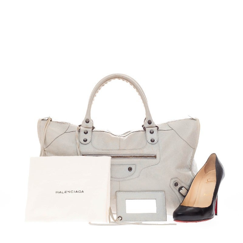 This authentic Balenciaga Work Classic Studs Leather is true to the brand's easy, luxe aesthetic. Crafted in light gray leather, this classic bag features a front zip pocket and accented with braided hand-stitched handles and buckle details. The top