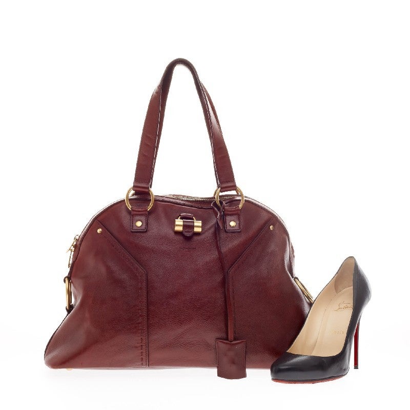 This authentic Saint Laurent Muse Shoulder Bag Leather Medium is perfect for everyday use. Constructed in burgundy red leather, this shoulder bag is accented with gold-tone hardware and features dual flat handles with protective base studs. Its