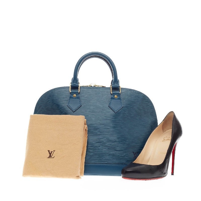 This authentic Louis Vuitton Alma Epi Leather PM is elegant and as classic as they come. Constructed with Louis Vuitton's signature sturdy toledo blue epi leather, this bag's structured and dome-like design is ideal for casual and special occasions.