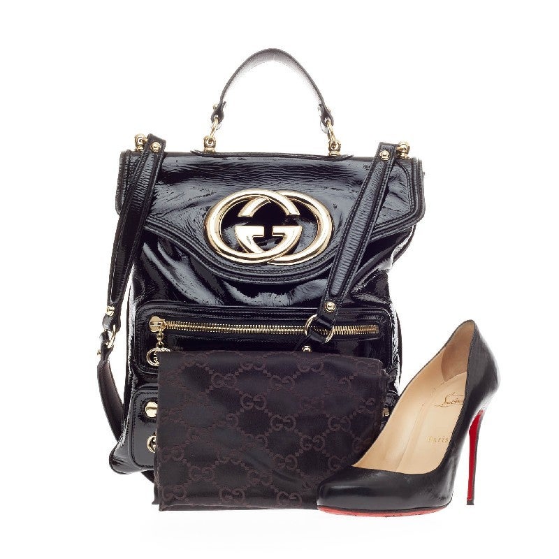 This authentic Gucci Britt Messenger Bag Patent is perfect for daring fashionistas. Crafted in black patent leather, this eye-catching elongated flat messenger features gold-tone hardware accents, oversized Gucci emblem, three front zipped pockets,